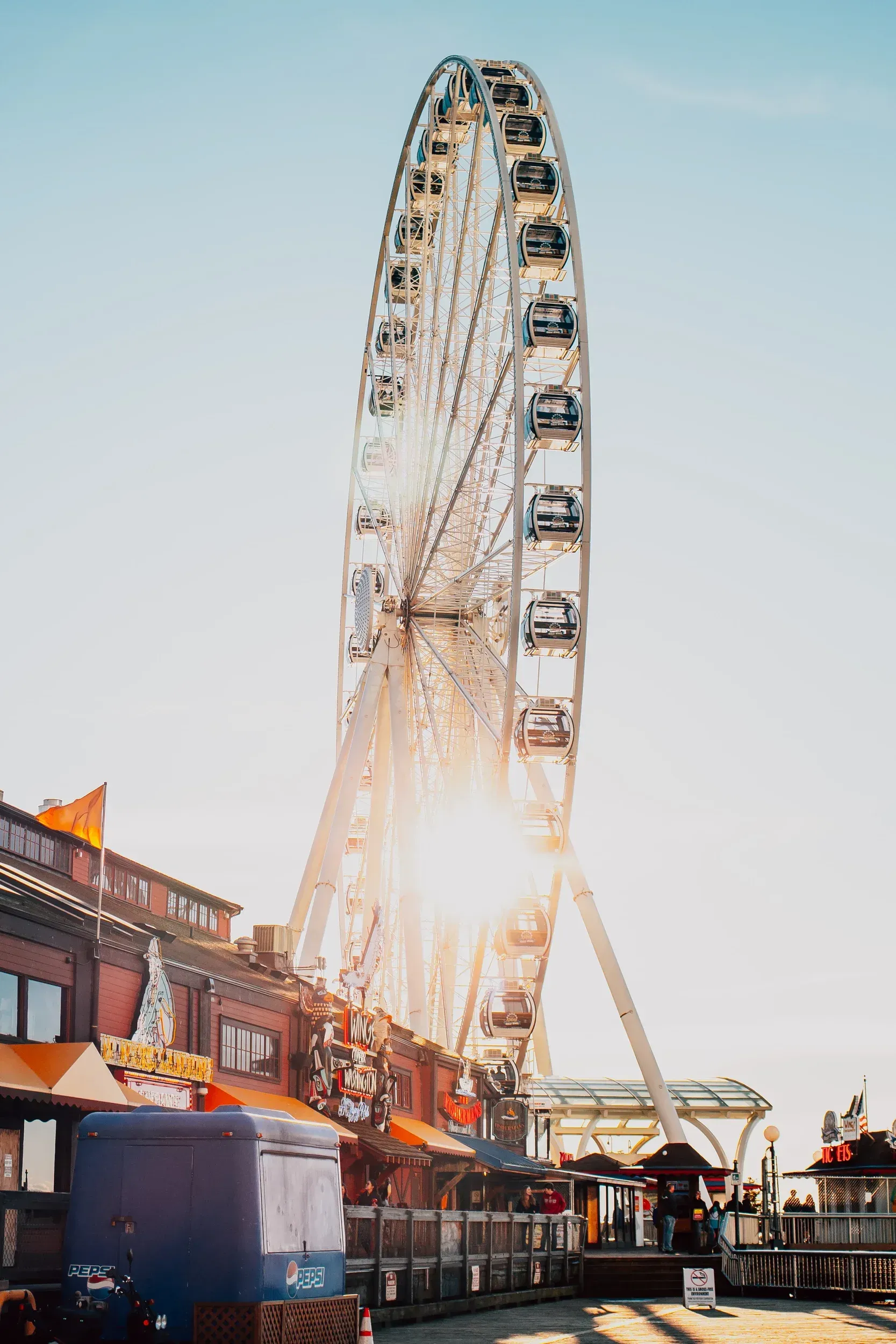 A ferris wheel is sitting in front of a building at an amusement park.