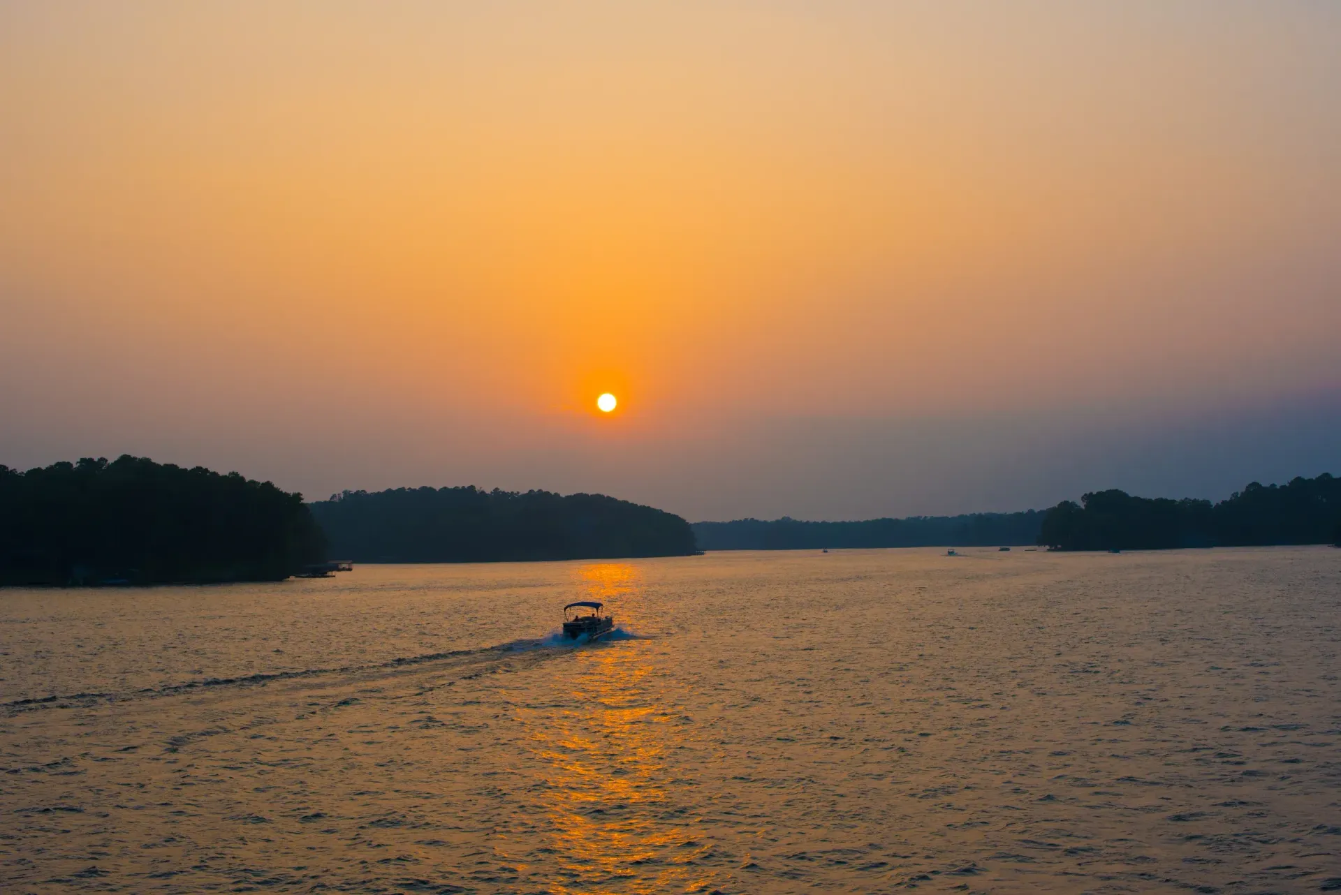 A boat is floating on a lake at sunset.