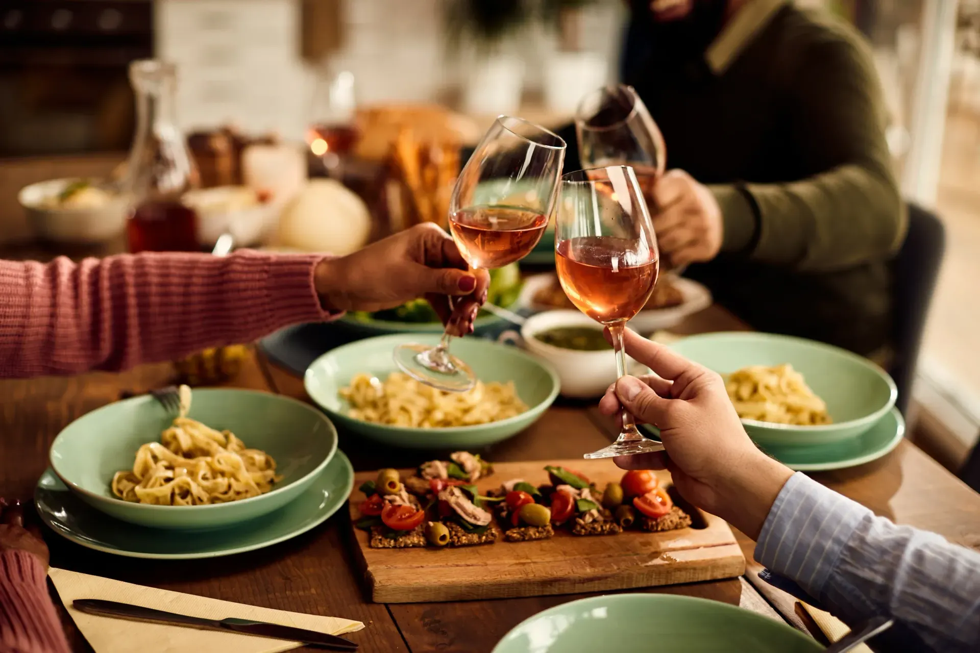 A group of people are sitting at a table eating food and drinking wine.