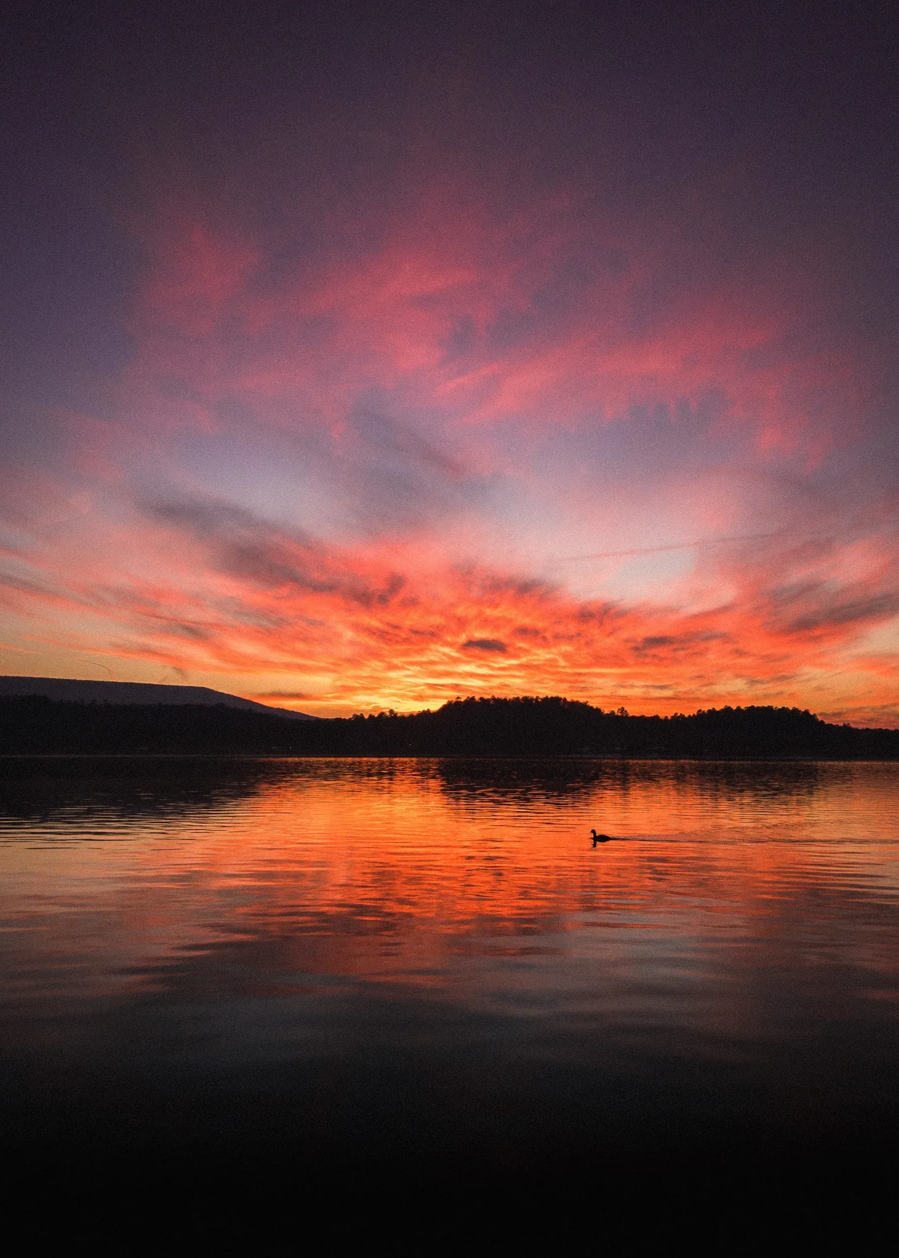 A sunset over a body of water with mountains in the background