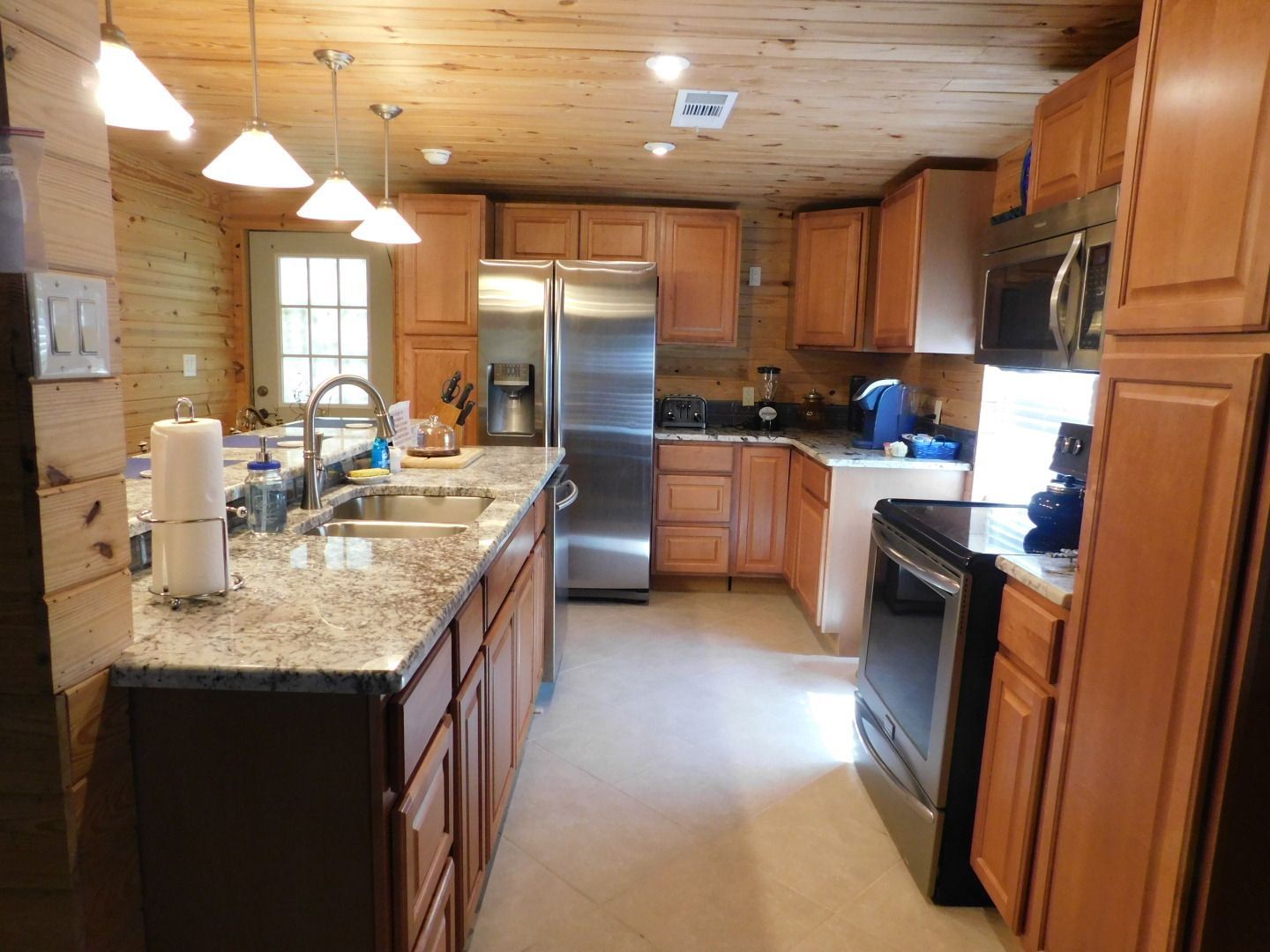 A kitchen in a log cabin with a large island in the middle.