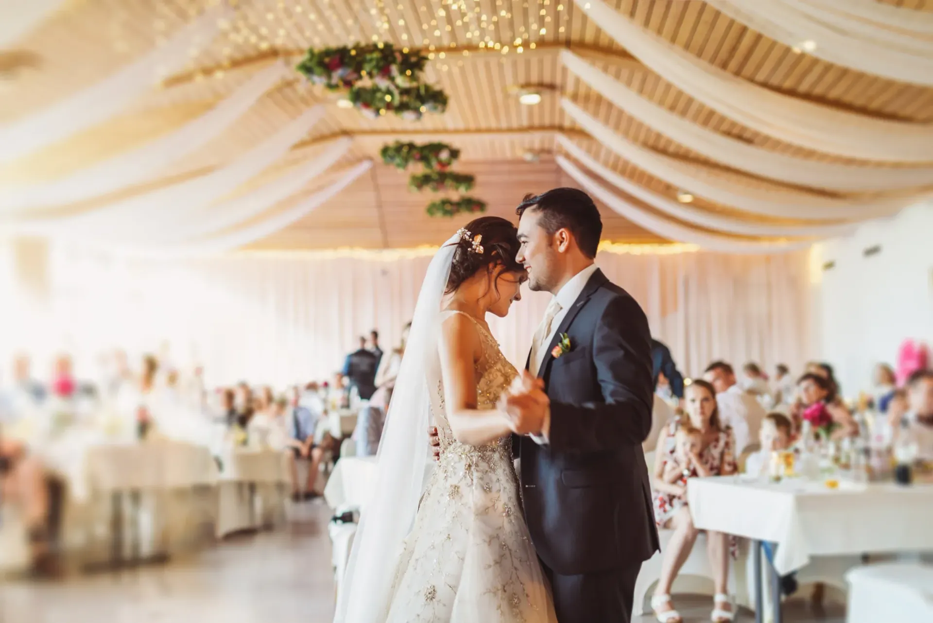 A bride and groom are dancing their first dance at their wedding reception.