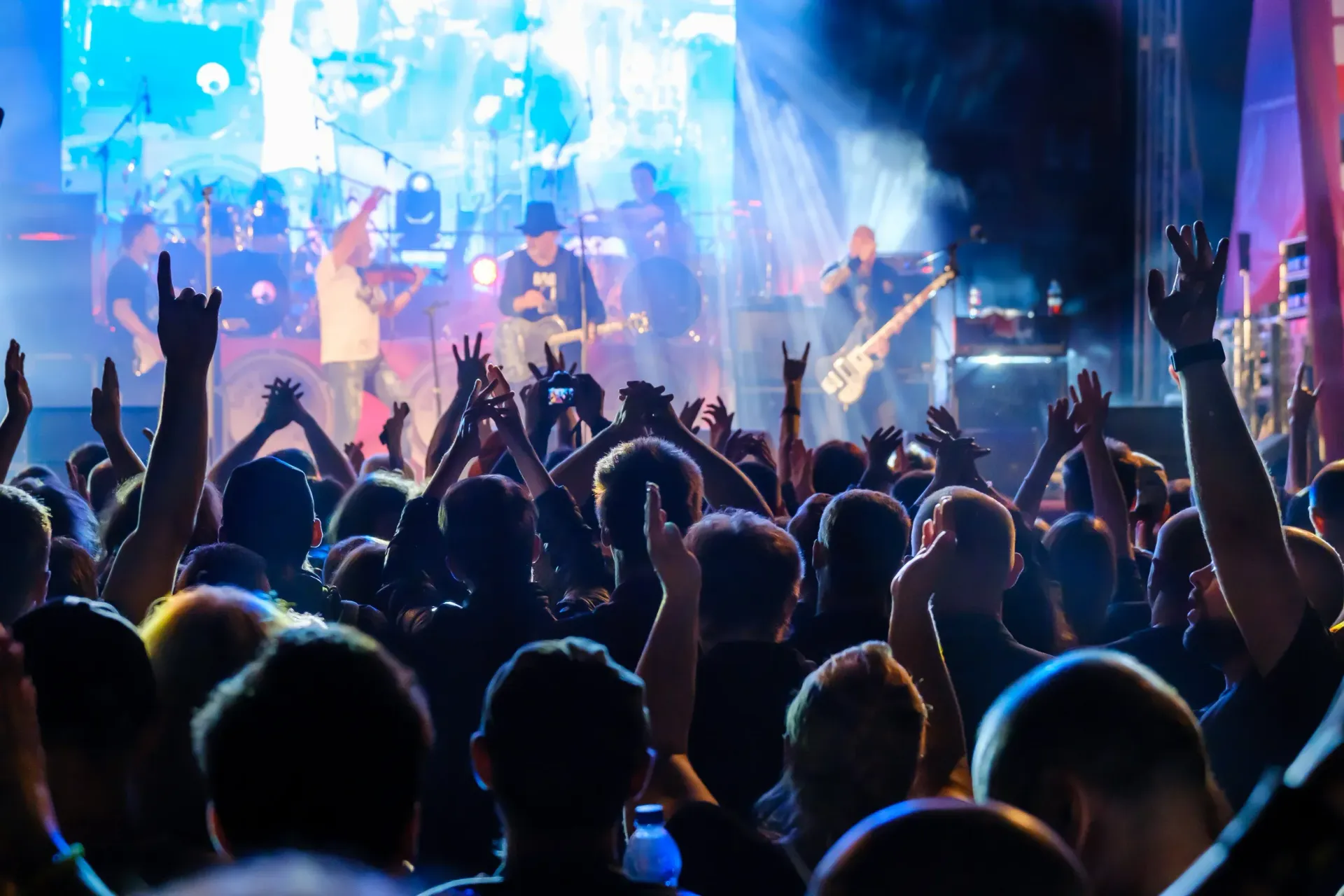 A crowd of people are standing in front of a stage at a concert.