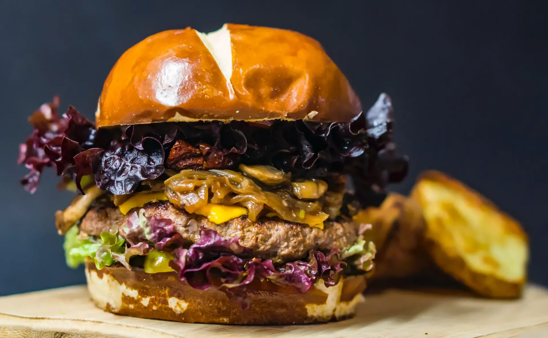 A close up of a hamburger on a wooden cutting board.