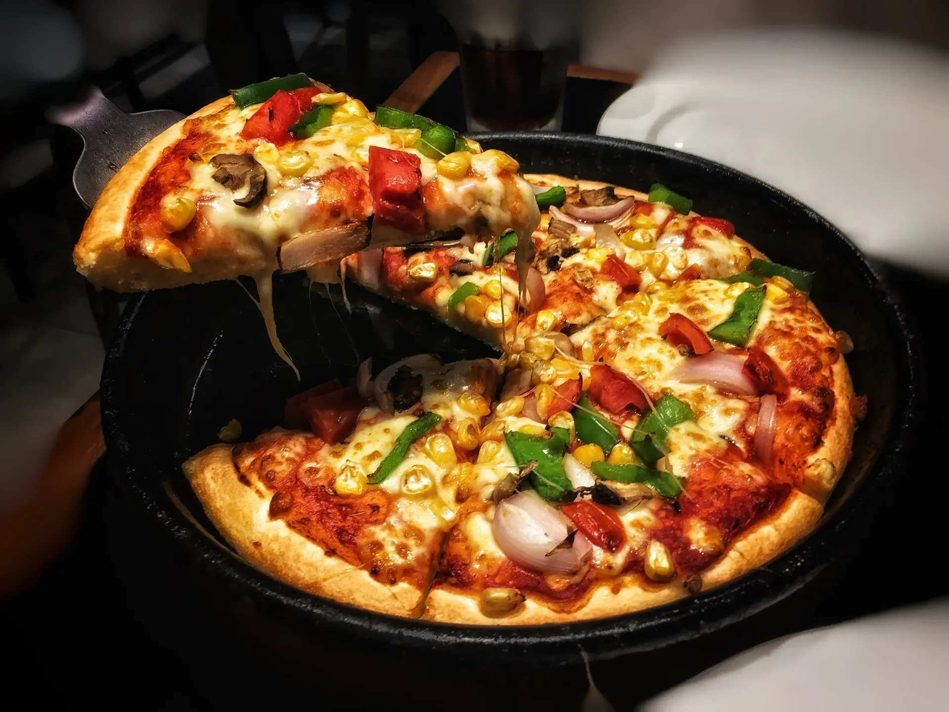 A slice of pizza is being taken out of a pizza pan.