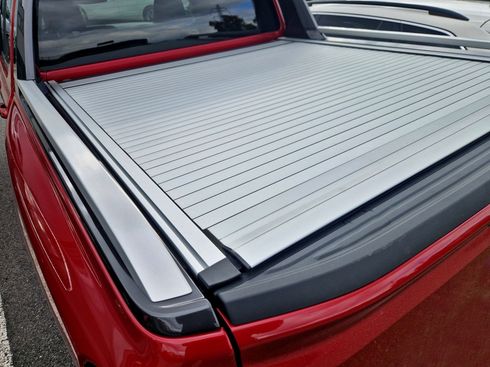 Red pickup truck bed with a silver roll-up tonneau cover closed