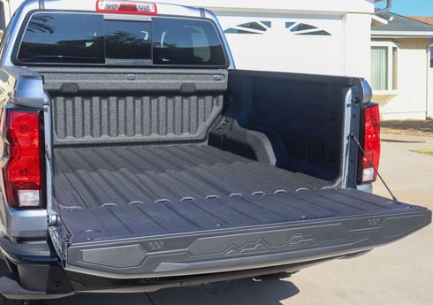 Pickup truck with open tailgate and bed liner, parked in a driveway