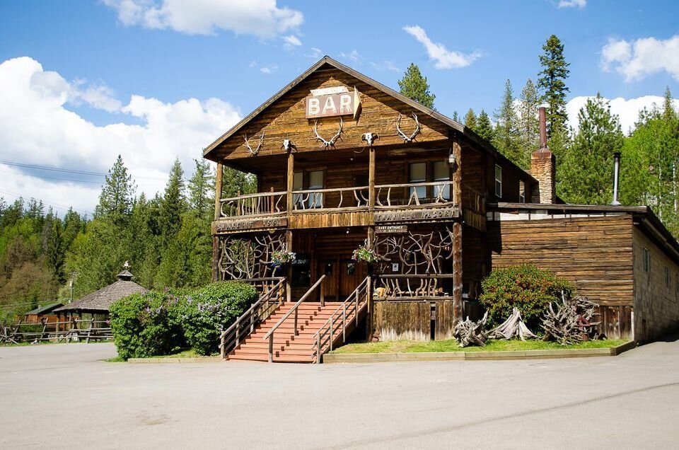 Rustic wooden bar with two-story porch, red stairs, and