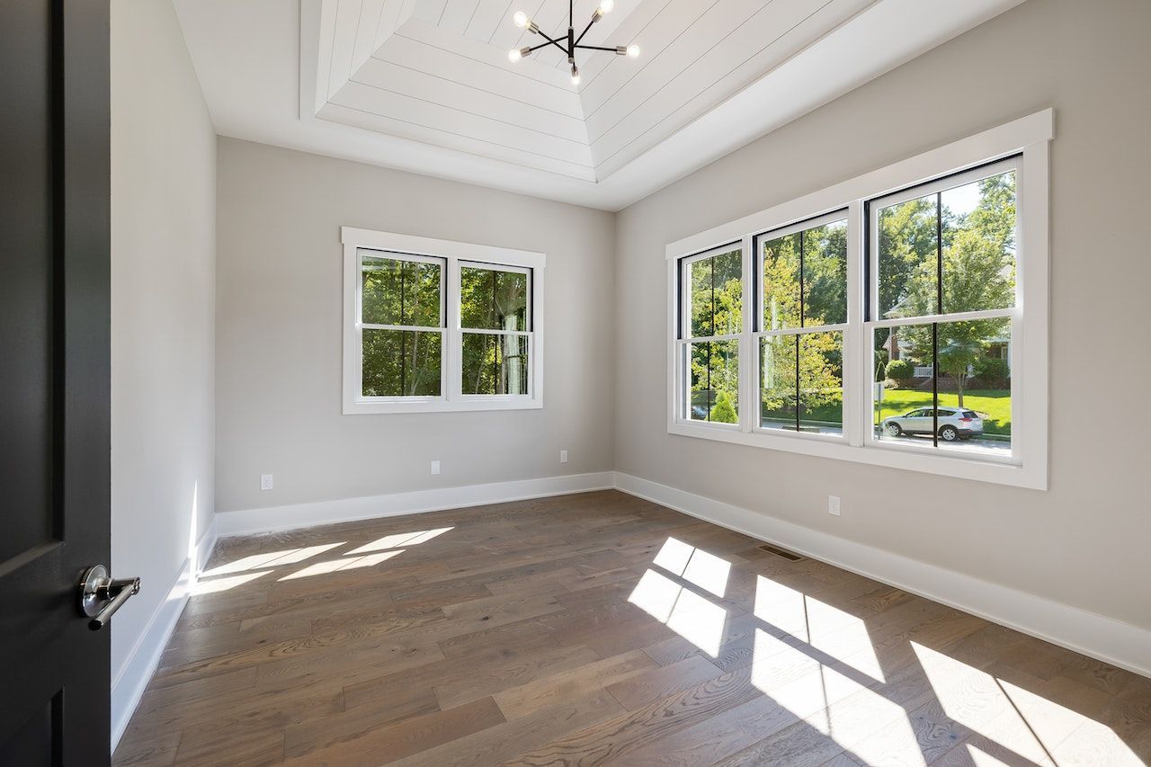 A large empty room with lots of windows and hardwood floors.