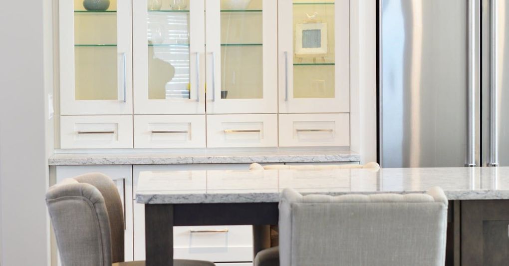 A kitchen with white cabinets , stainless steel appliances , a table and chairs.