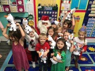 A group of children are posing for a picture with santa claus and holding stuffed animals.