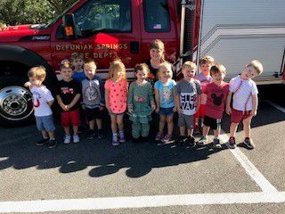 A group of children are standing in front of a fire truck.