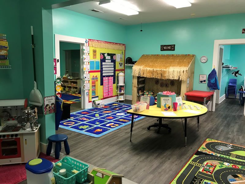 A play room with a table , chairs , and toys.
