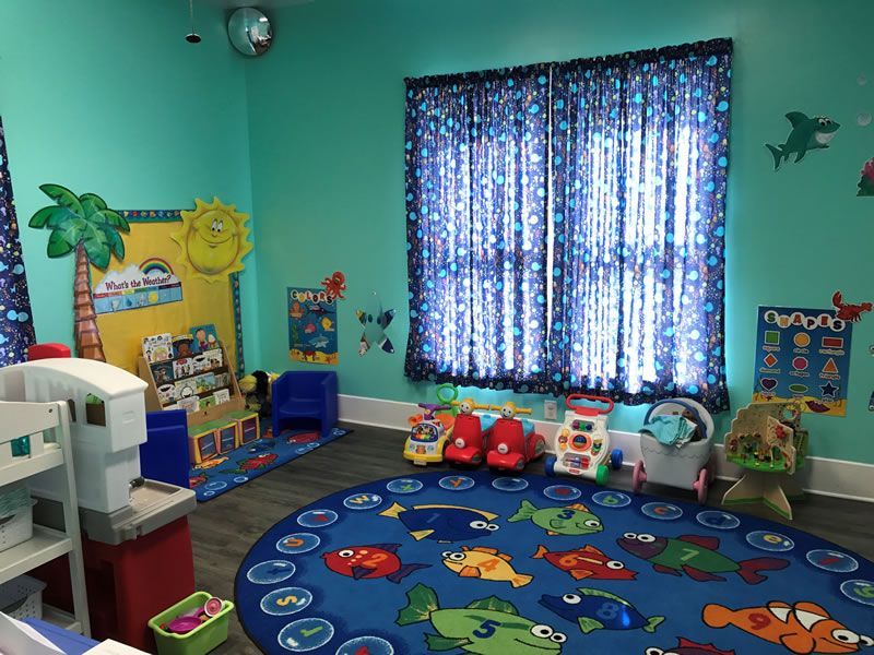 A child 's room with a blue rug and toys.