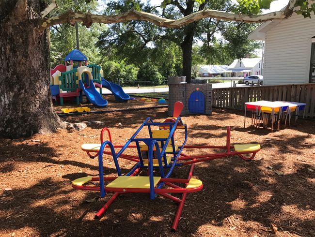 A colorful merry go round sits in the middle of a playground.