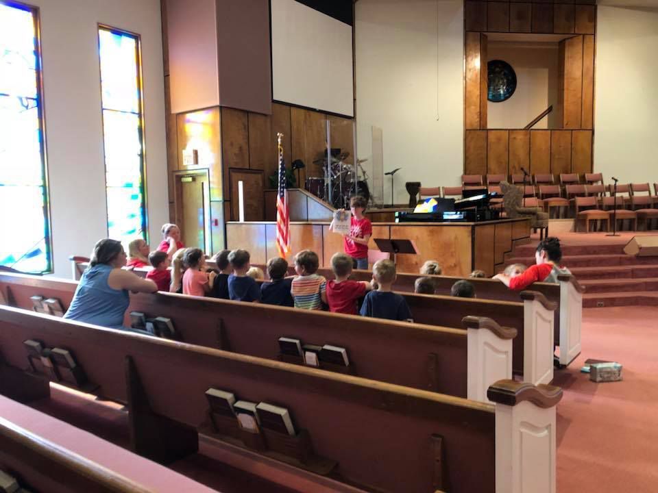 A group of children are sitting in a church.