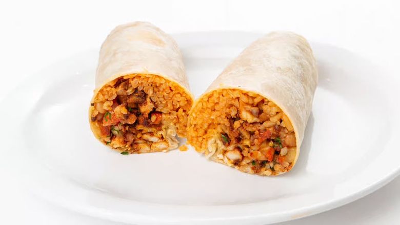 Two burritos cut in half on a white plate, showing a seasoned rice and bean filling.