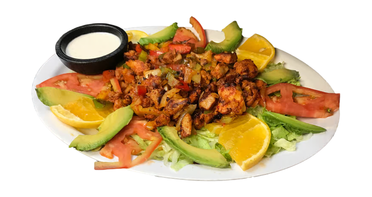 Grilled meat fajita platter with avocado, tomato, lime wedges, and dipping sauce