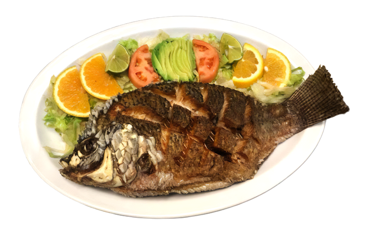 Whole grilled fish on a white platter, garnished with orange and lemon slices and vegetables