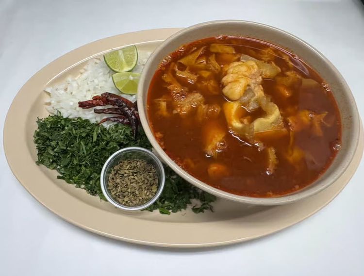 Curry dish with rice, herbs, dried chilies, and lime wedges on a plate