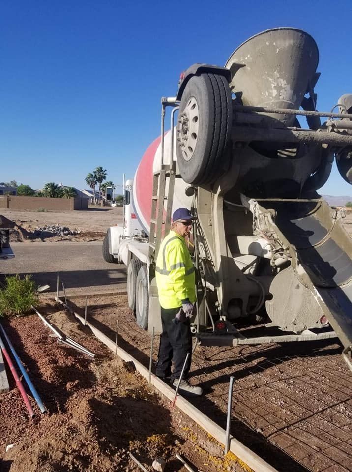 A man is standing in front of a concrete mixer truck.