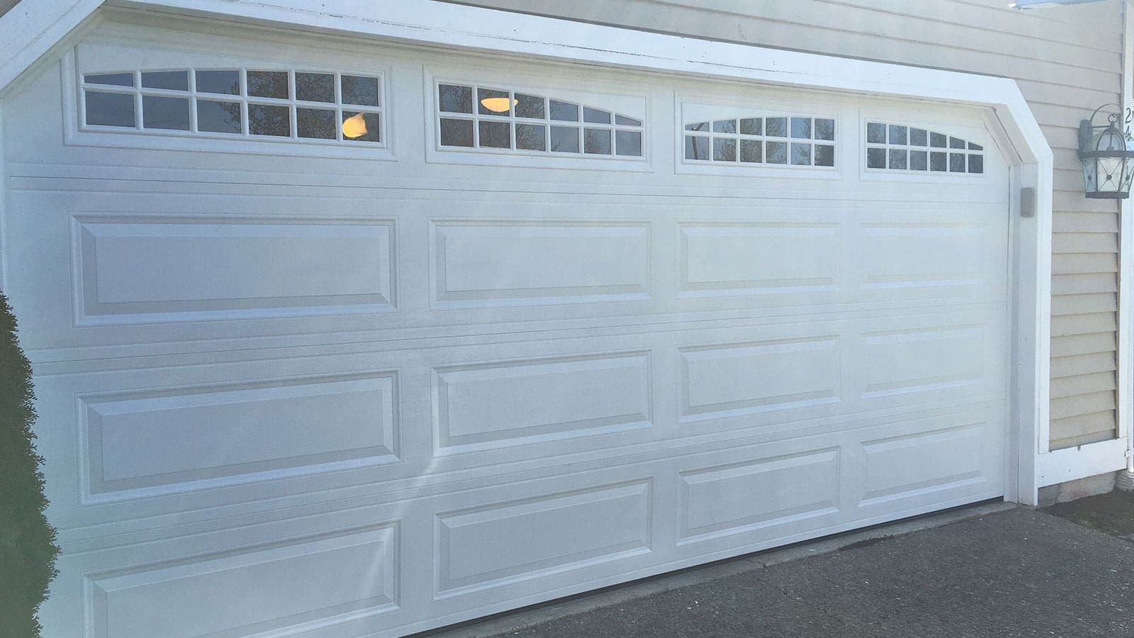A white garage door with rectangular panels and a top row of small, grid-patterned windows.