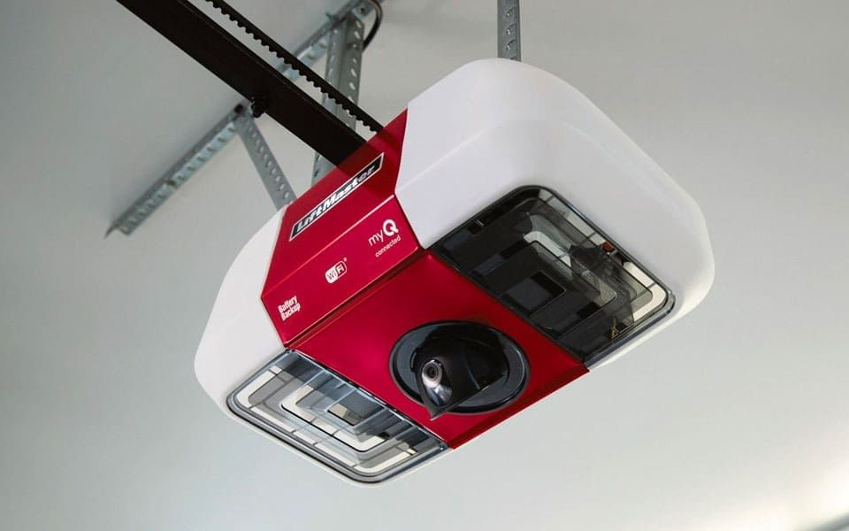 A Chamberlain garage door opener with a red casing and built-in camera, mounted to a garage ceiling.