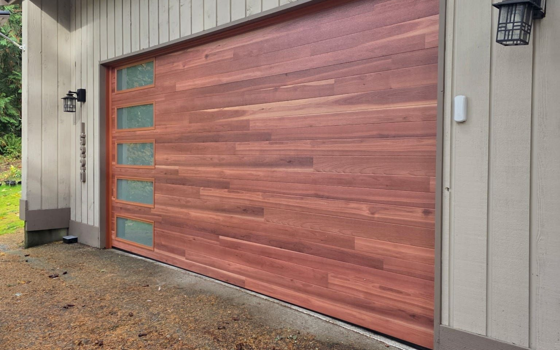 A horizontal wooden garage door with a vertical row of five rectangular frosted glass panels on the left side.