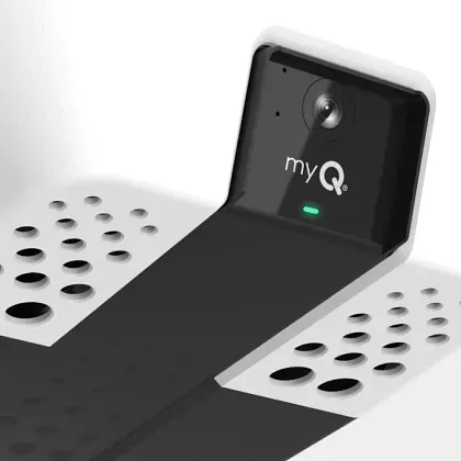 A black and white myQ smart garage camera mounted on a garage door rail.