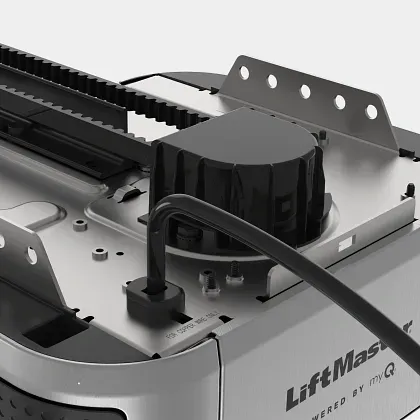 A close-up view of the top of a silver LiftMaster garage door opener motor with a black drive belt and power cord.