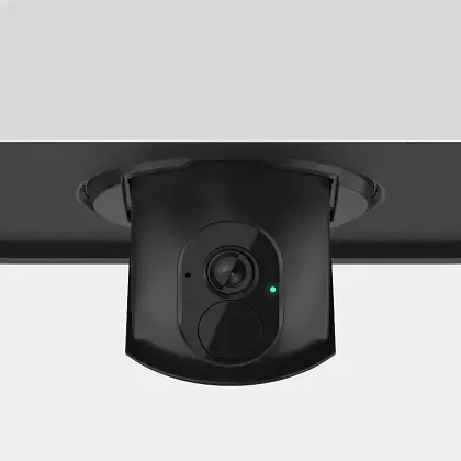 A black ceiling-mounted security camera with a small green status light, viewed from below against a white background.
