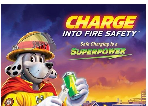 Fire safety poster with a cartoon firefighter dog charging a green phone, “Charge into fire safety: safe charging is superpower.”