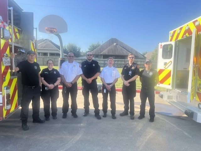 Manvel and BCESD3 personnel stand between standing between a fire trucks and an ambulance.