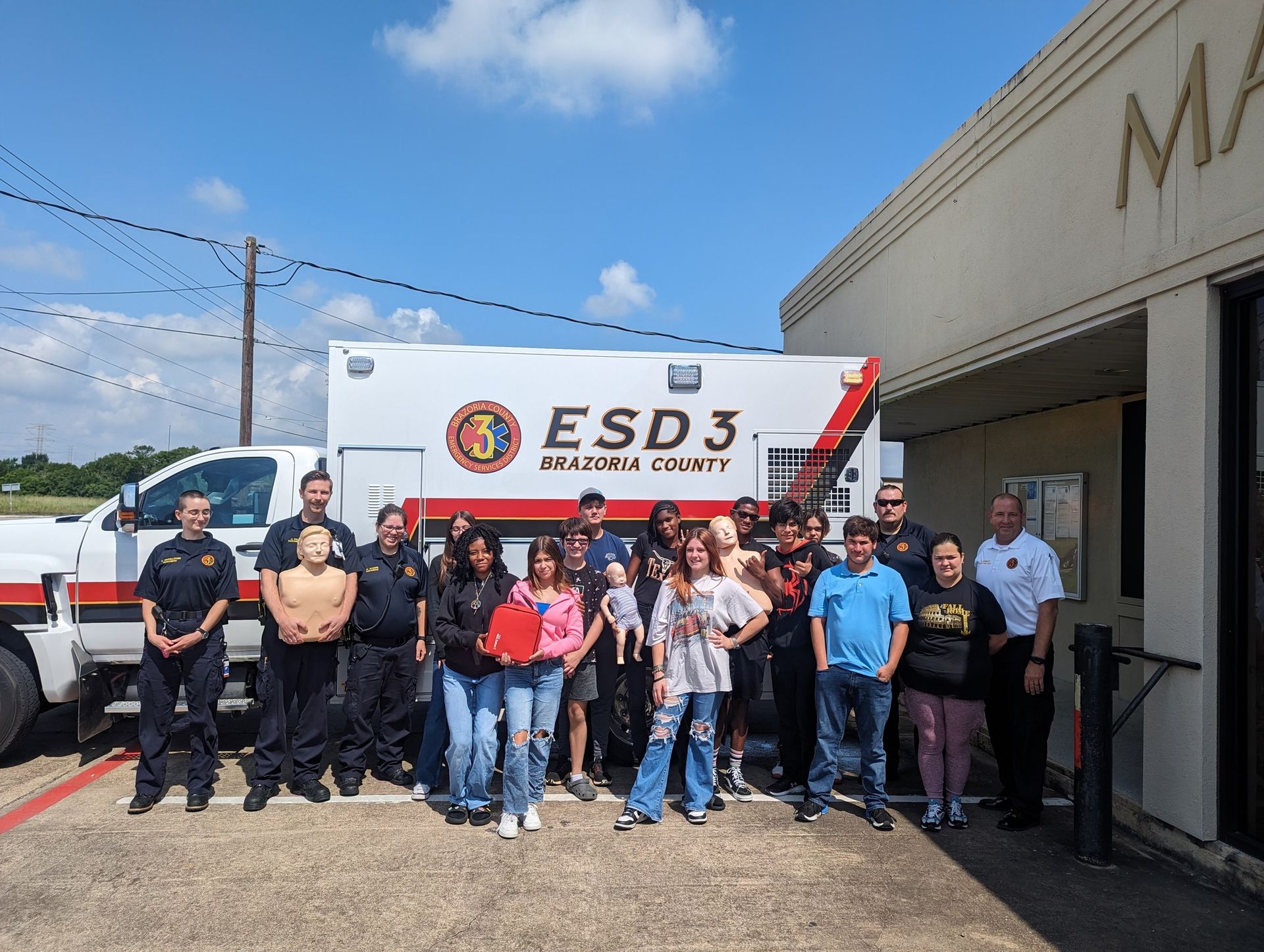 A group of people are posing for a picture in front of an ambulance.