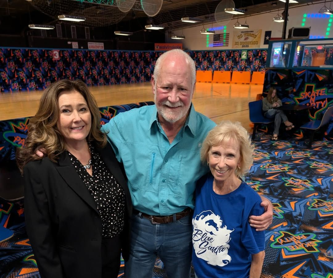 Three smiling people posing on a colorful patterned floor in an indoor entertainment venue.