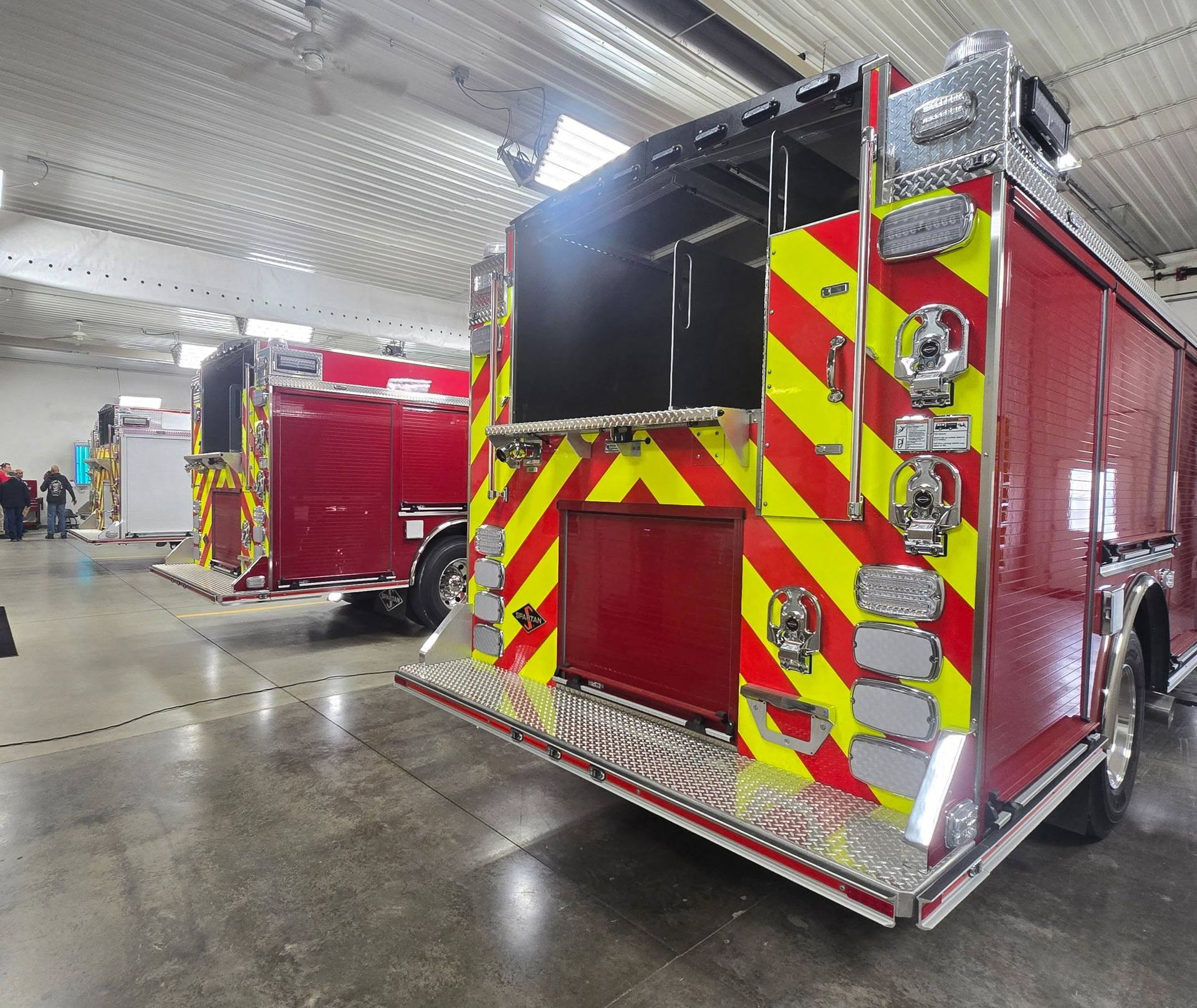 A picture of the back of 2 fire engines with red and yellow striping