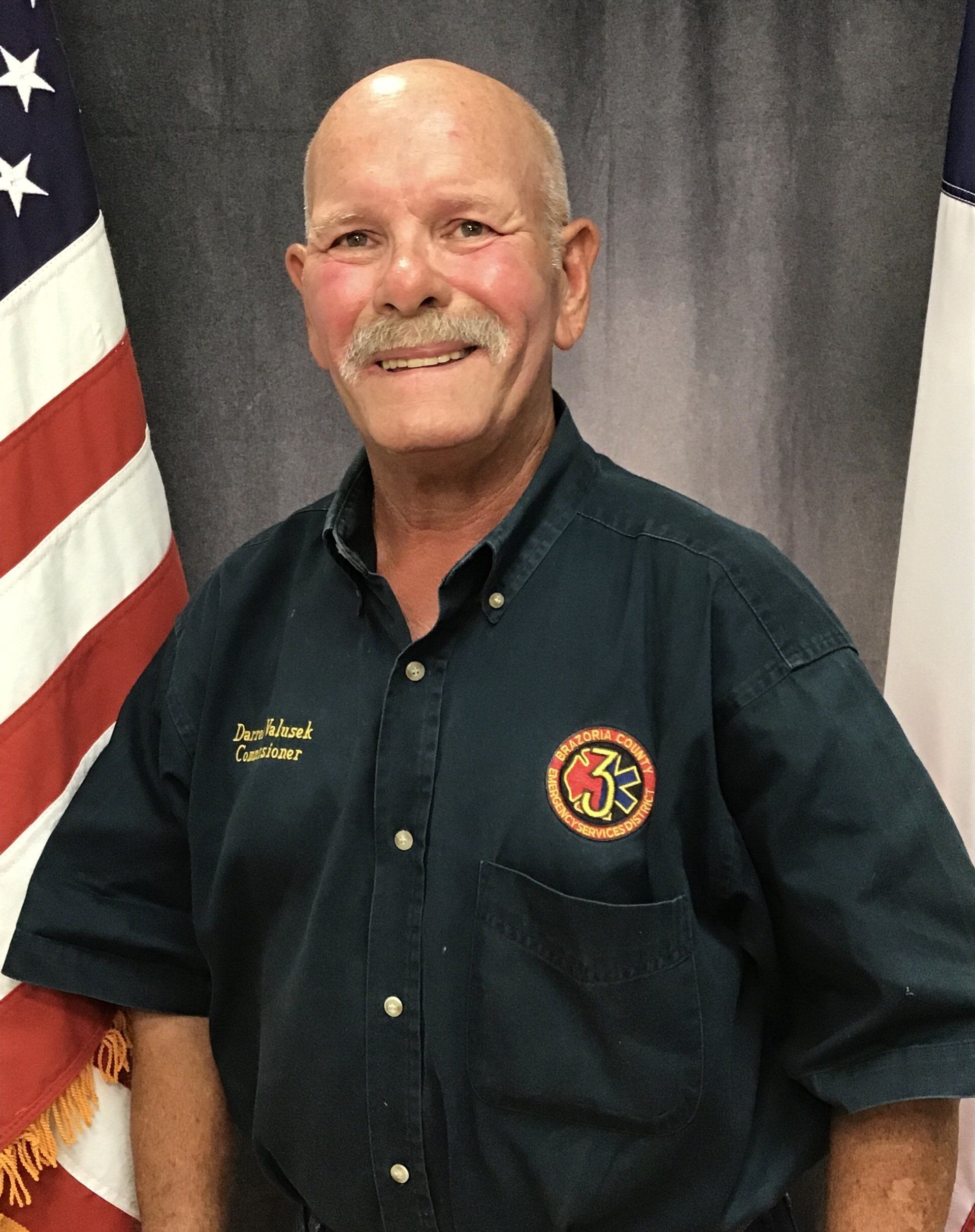 A picture of a Brazoria County ESD 3 commissioner in front of an American flag.