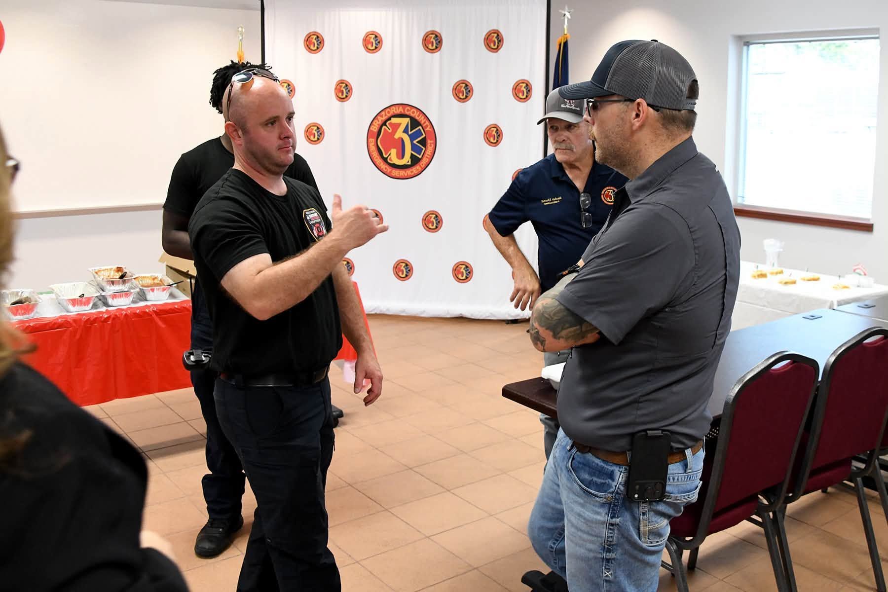 People talking in a room with a wall banner and tables of items