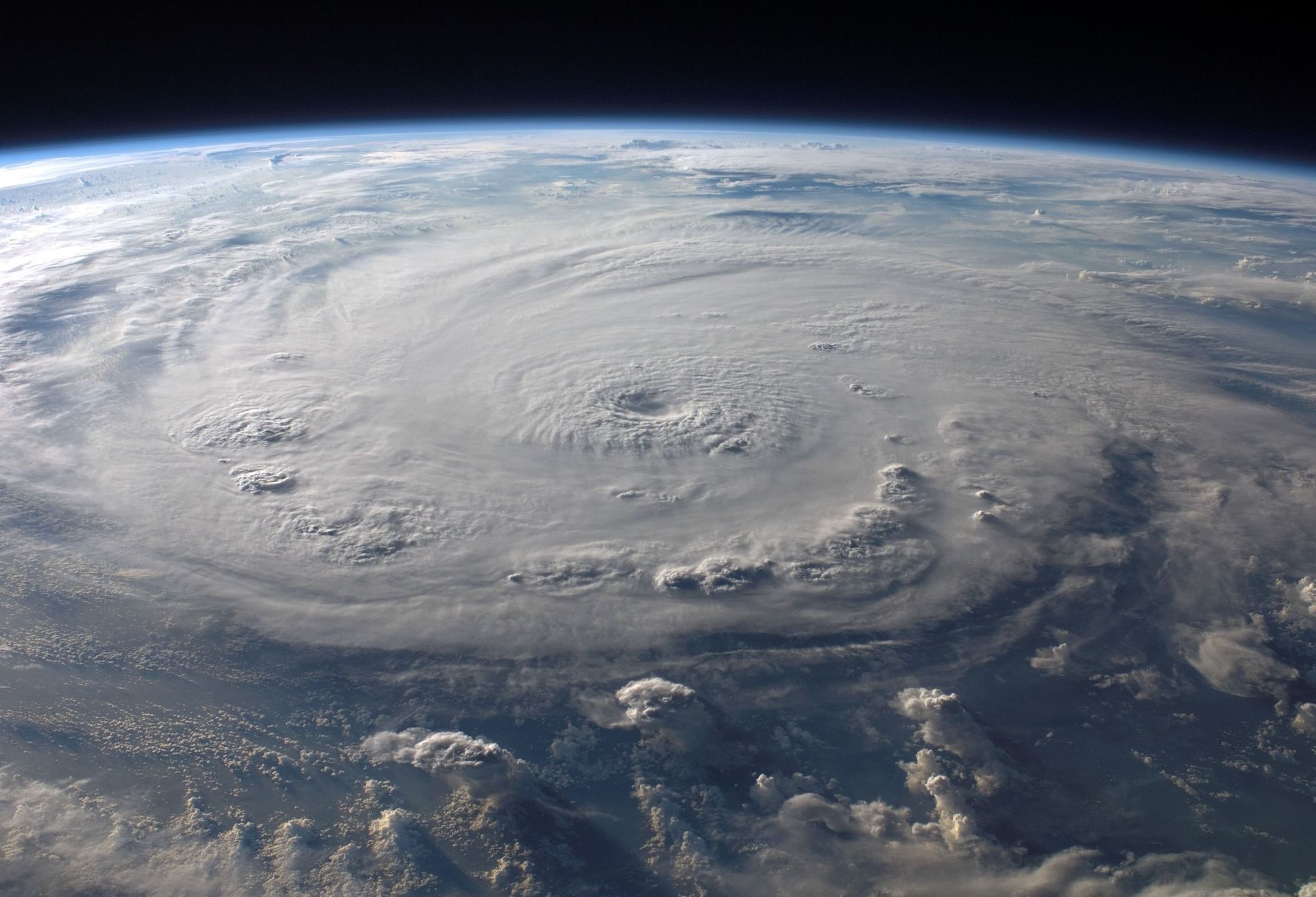 Massive hurricane swirling over the ocean, seen from space with a dark eye and white cloud bands
