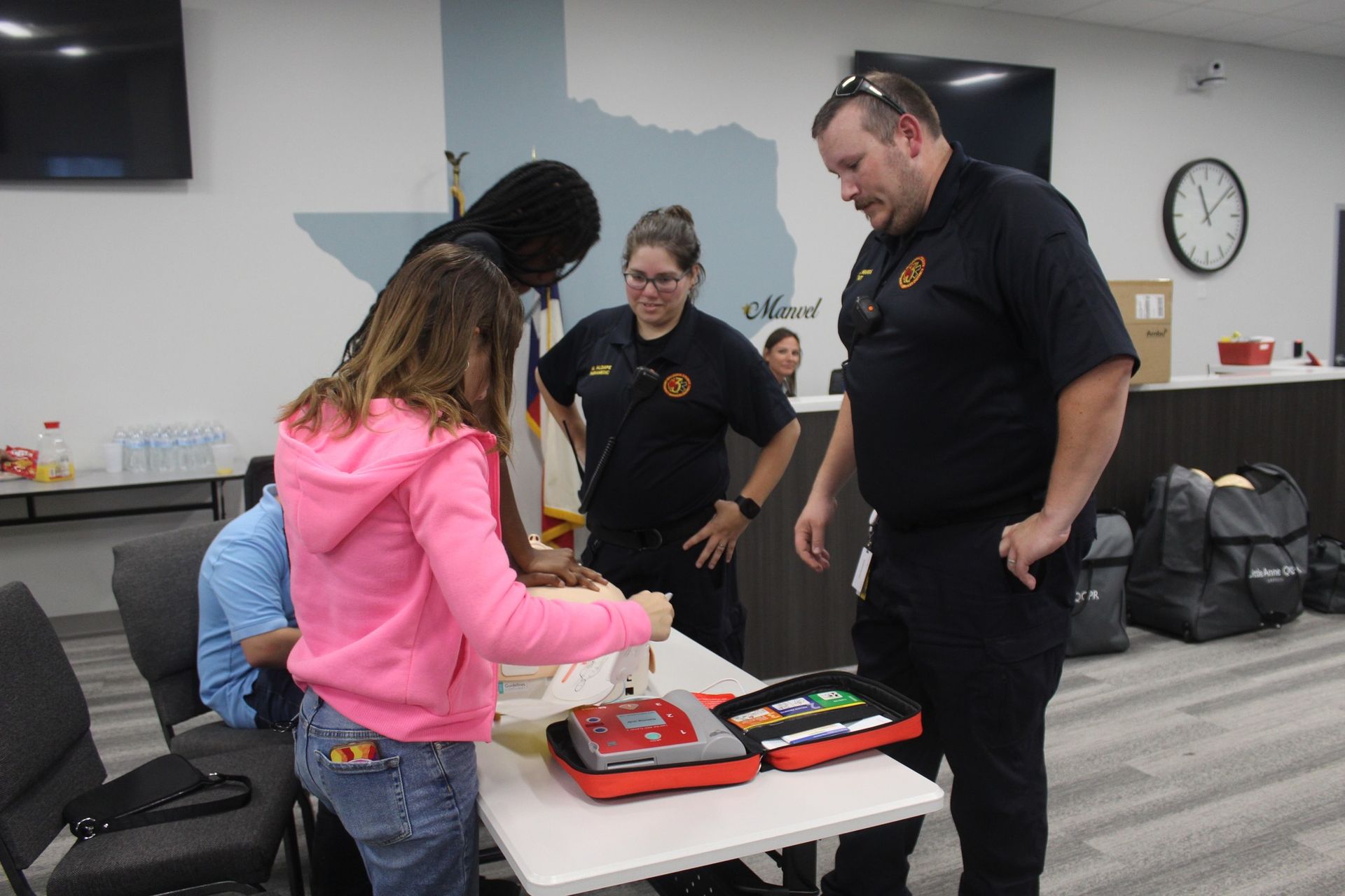 A group of people are standing around a table with a defibrillator on it.