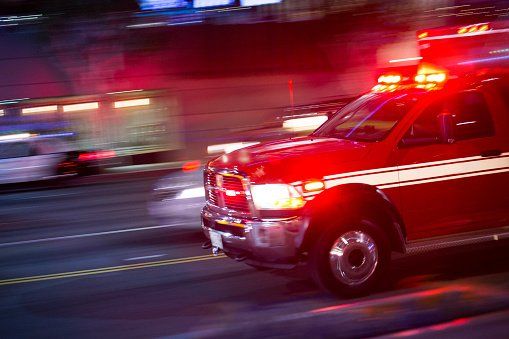 An ambulance is driving down a city street at night.