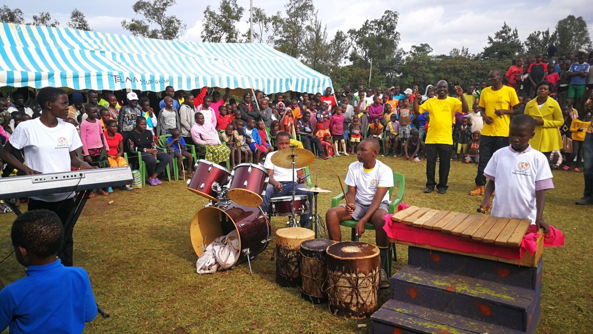 A group of people are playing drums and xylophones in a field.