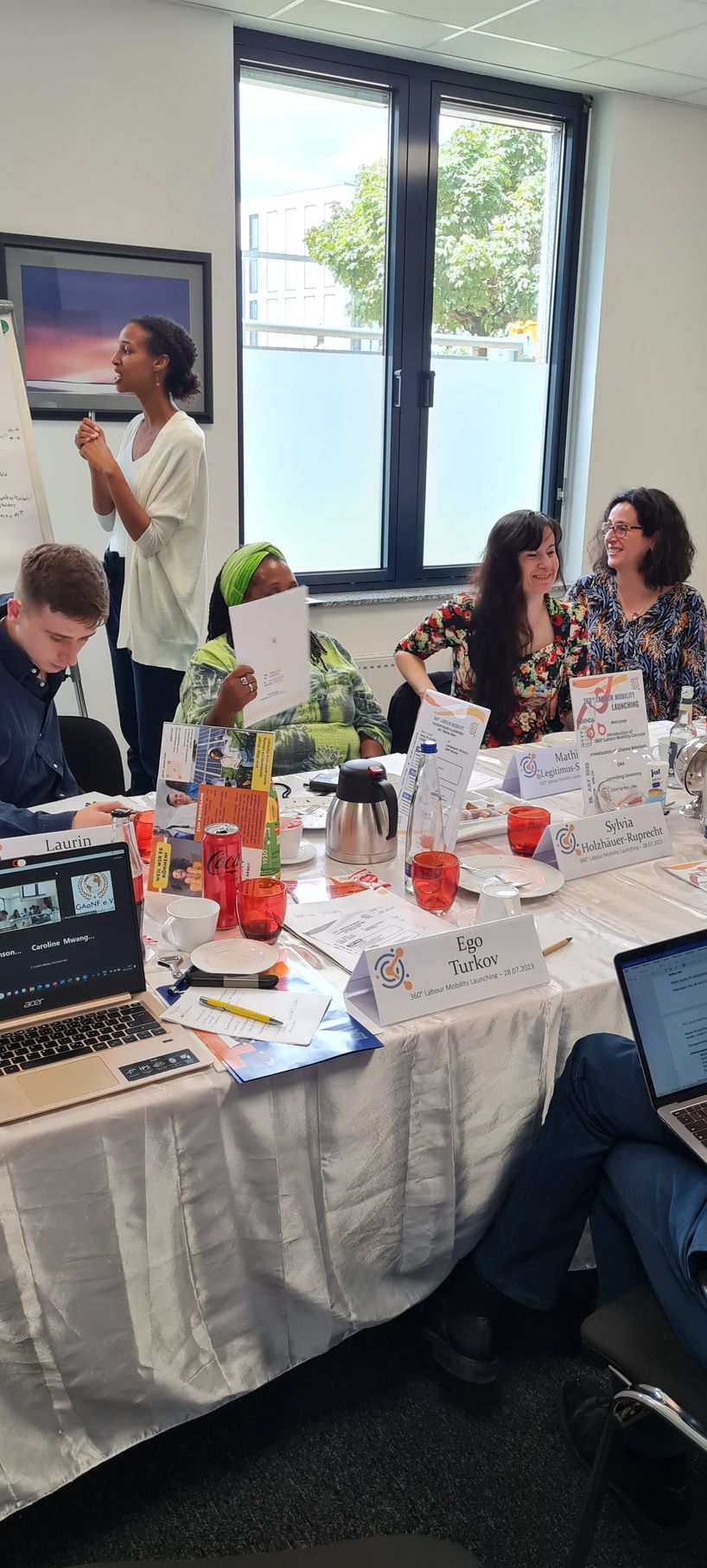 A group of people are sitting around a table with laptops.