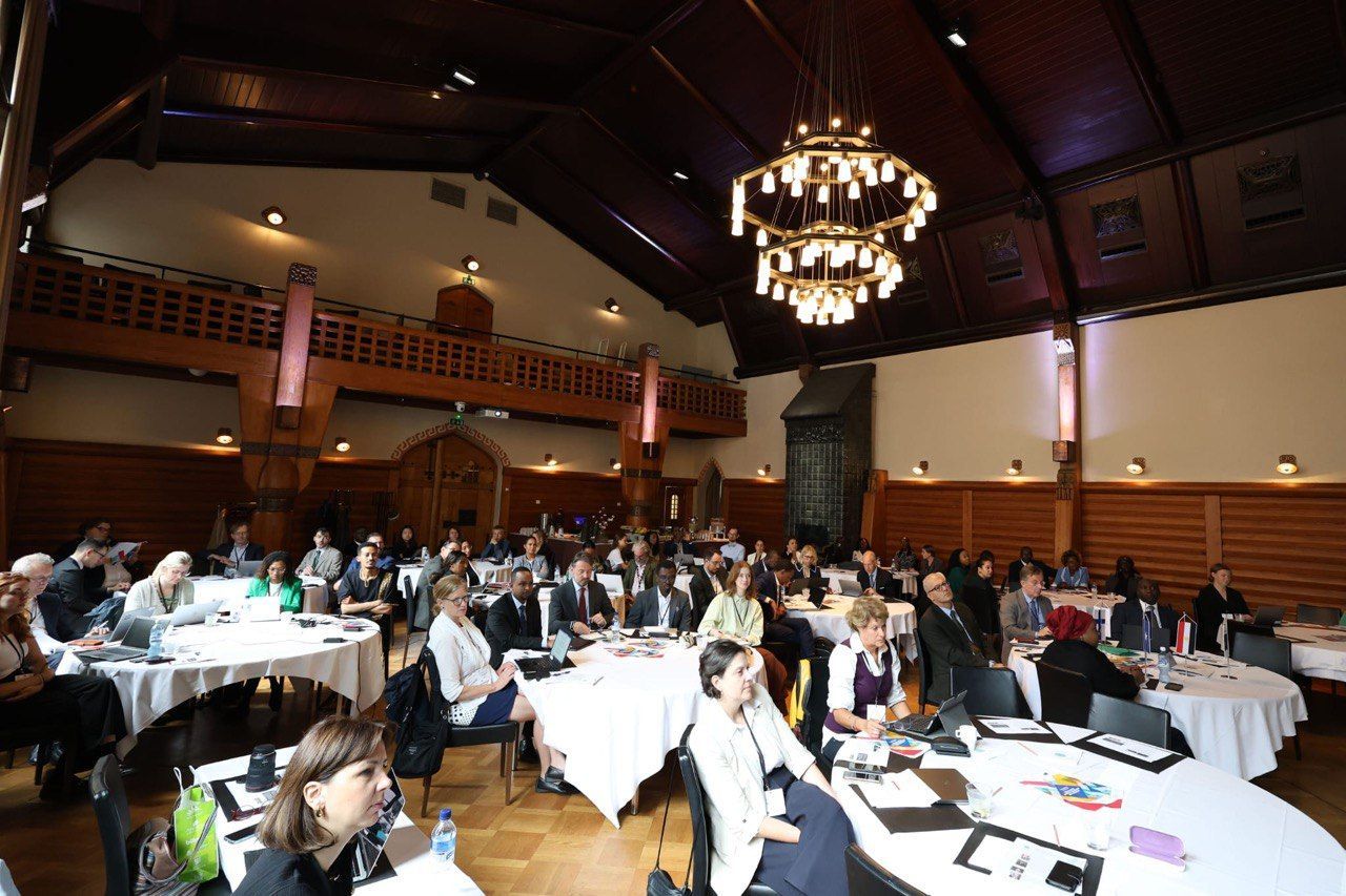 A group of people are sitting at tables in a large room.