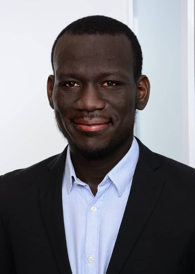 A man in a suit and blue shirt is smiling for the camera.