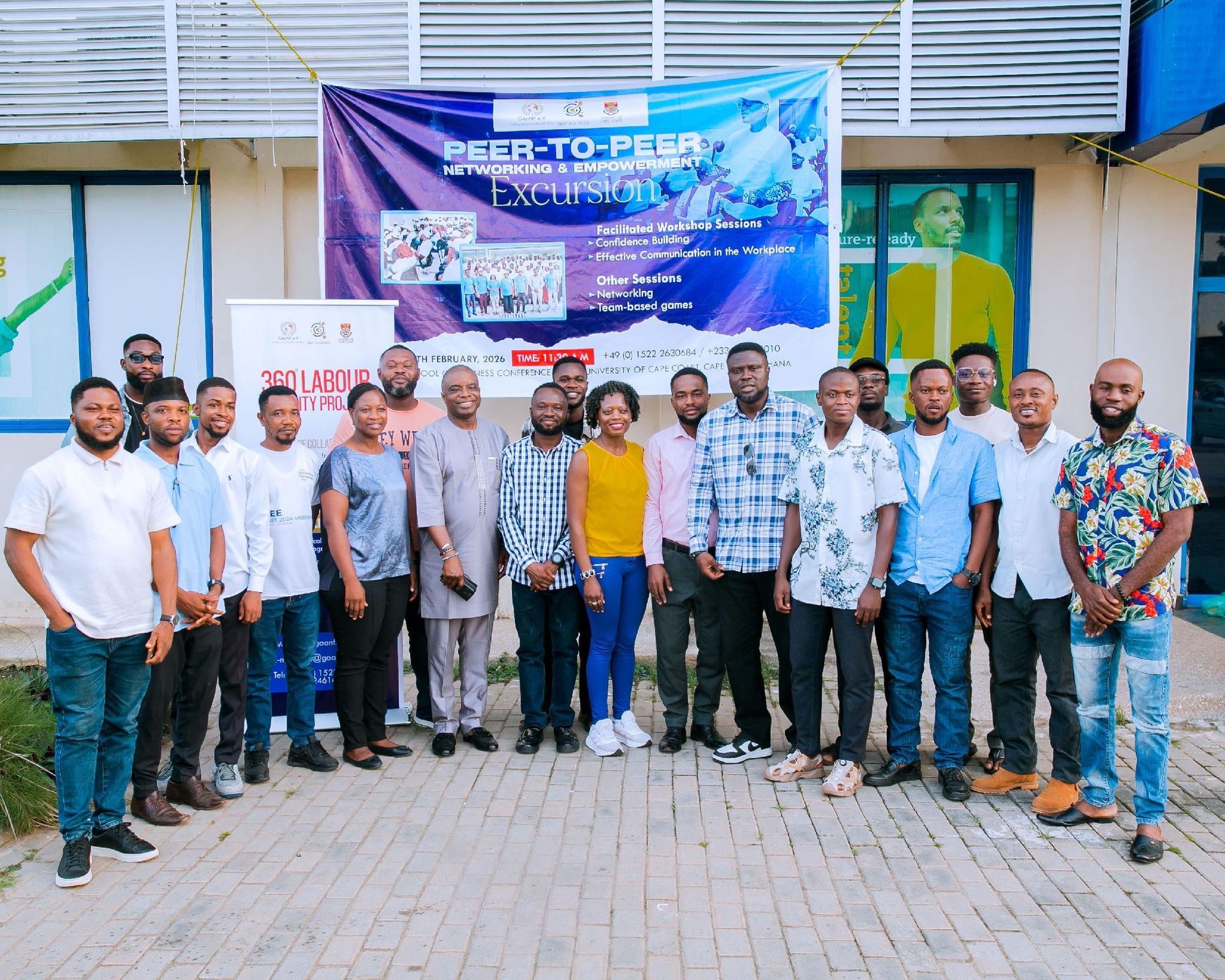 Group of people posing in front of a “User-to-Peer” event banner outdoors