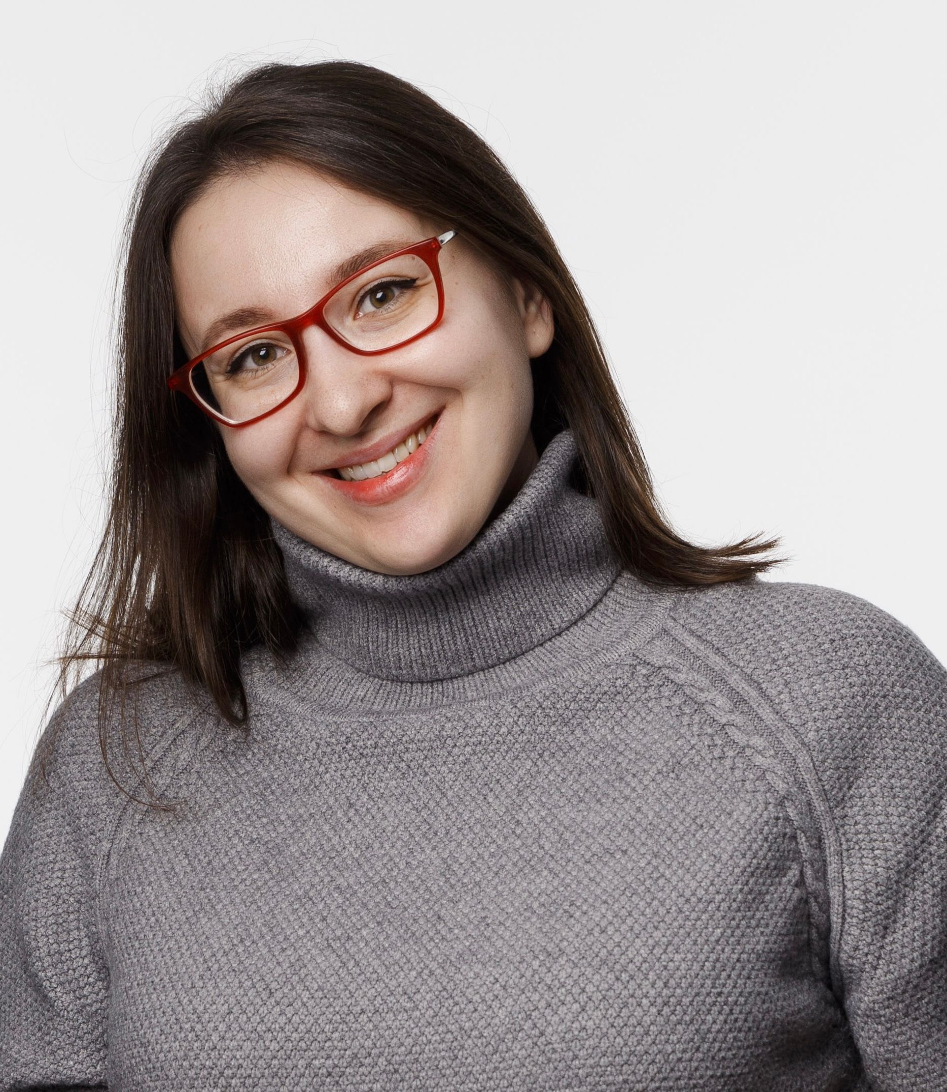 A woman wearing glasses and a turtleneck sweater is smiling.