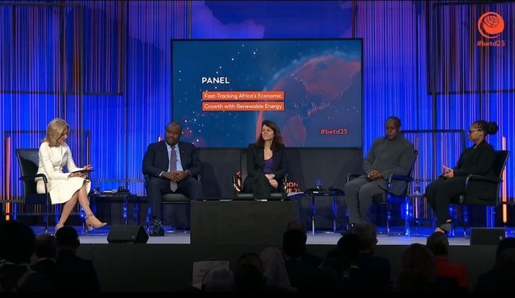 Panel discussion on stage with five people. Blue backdrop, audience in foreground.