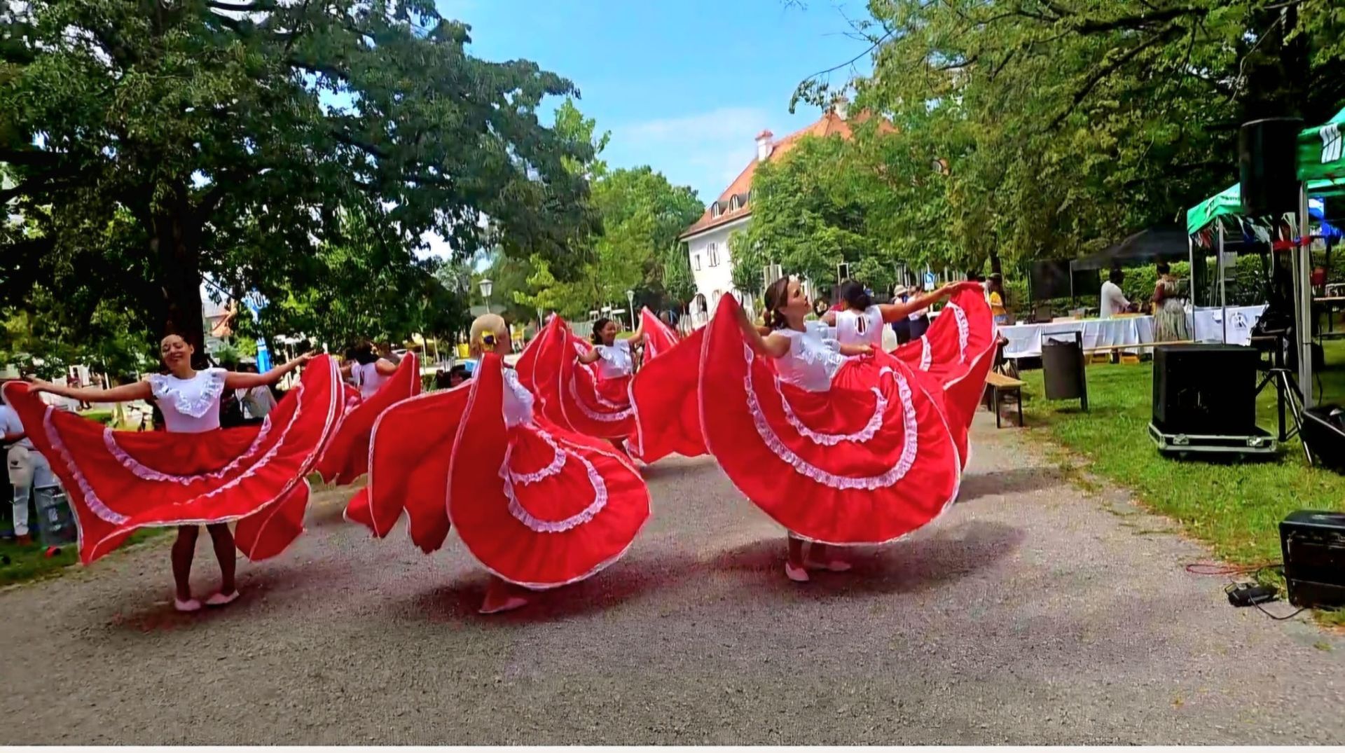 A group of women in red dresses are dancing in a park