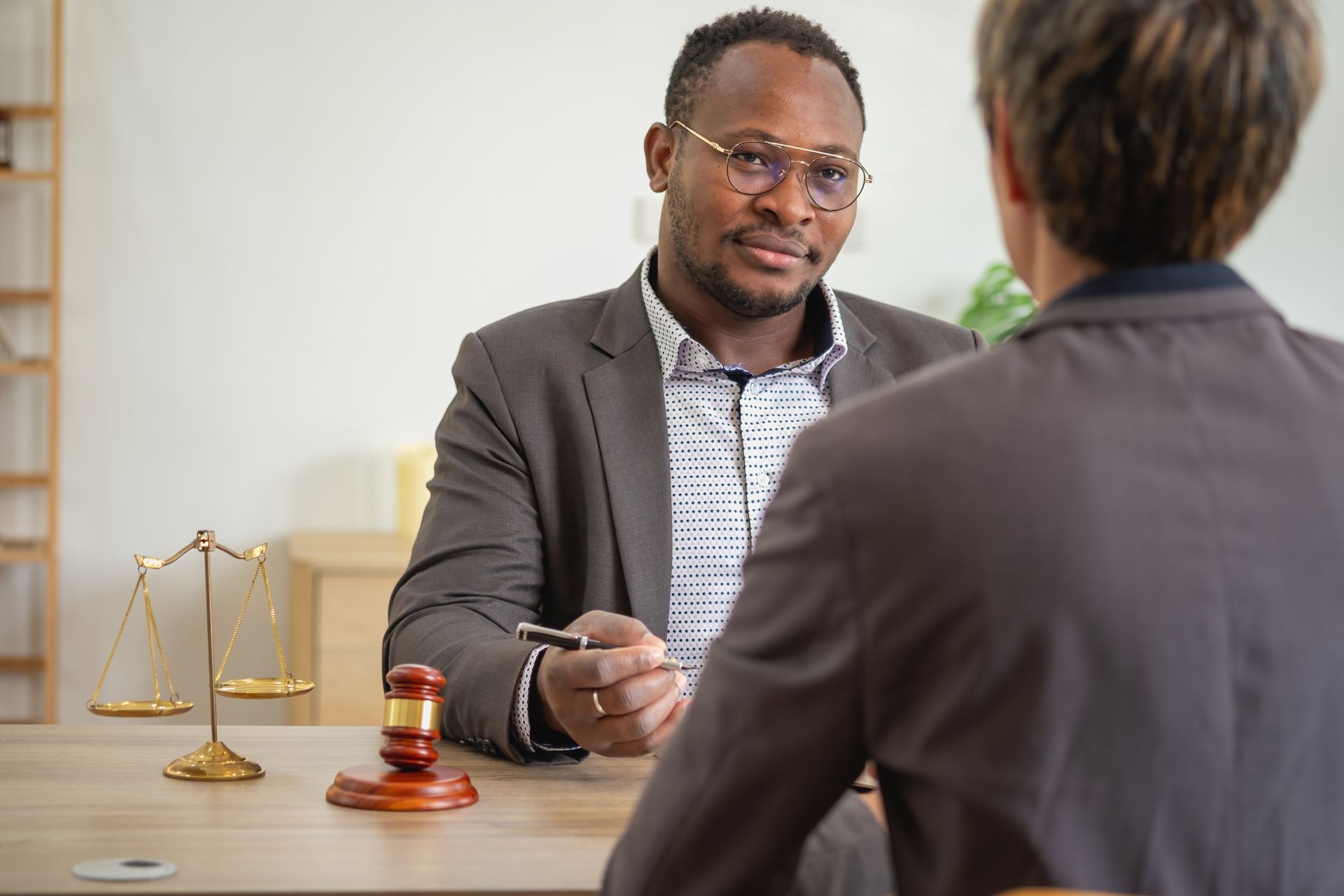 A man is sitting at a table talking to another man.